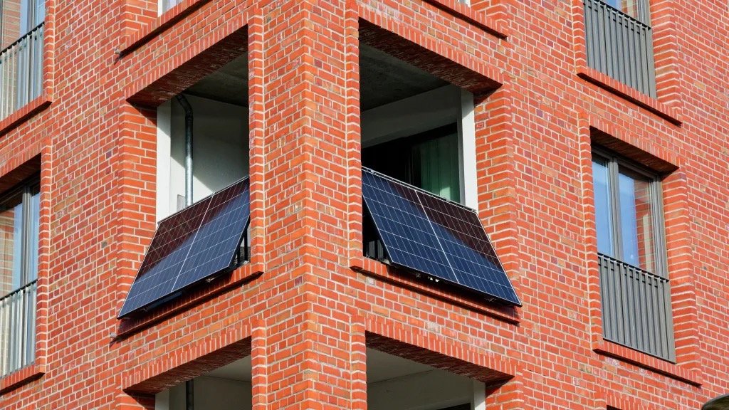 Plug-in solar panels mounted on the balconies of a brick apartment building